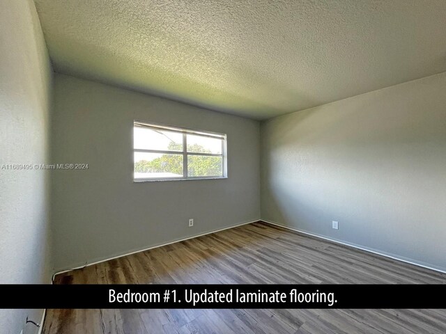 empty room with wood-type flooring and a textured ceiling