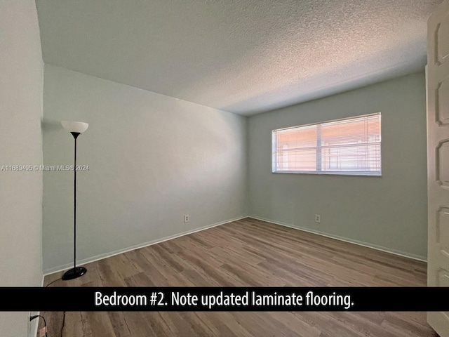 spare room with a textured ceiling and light hardwood / wood-style floors