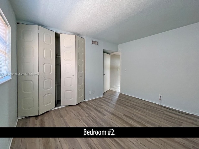 unfurnished bedroom with a textured ceiling and hardwood / wood-style flooring