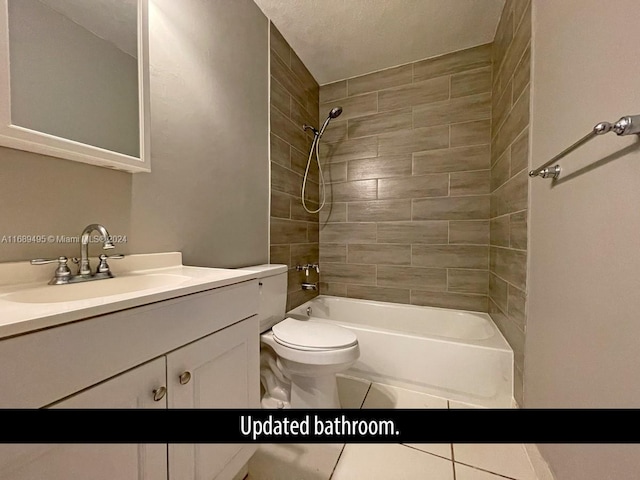 full bathroom featuring toilet, tile patterned flooring, tiled shower / bath, a textured ceiling, and vanity