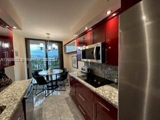 kitchen with stainless steel appliances, light stone counters, a notable chandelier, backsplash, and pendant lighting