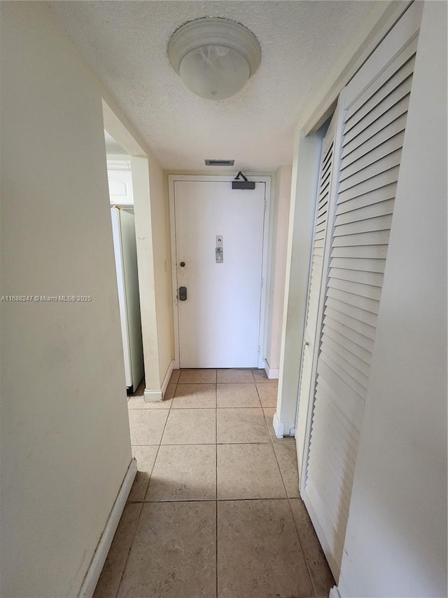 corridor featuring light tile patterned floors and a textured ceiling