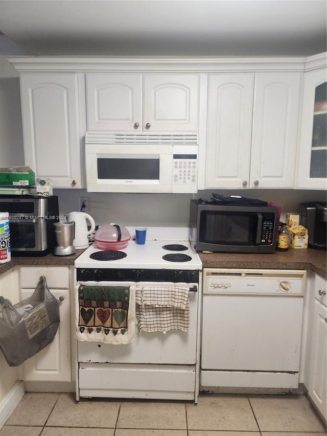 kitchen with white appliances, white cabinetry, and light tile patterned flooring