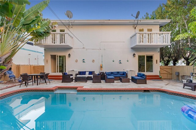 back of house featuring outdoor lounge area, a balcony, a patio, and a fenced in pool