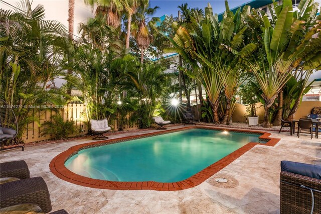 pool at dusk featuring a patio area