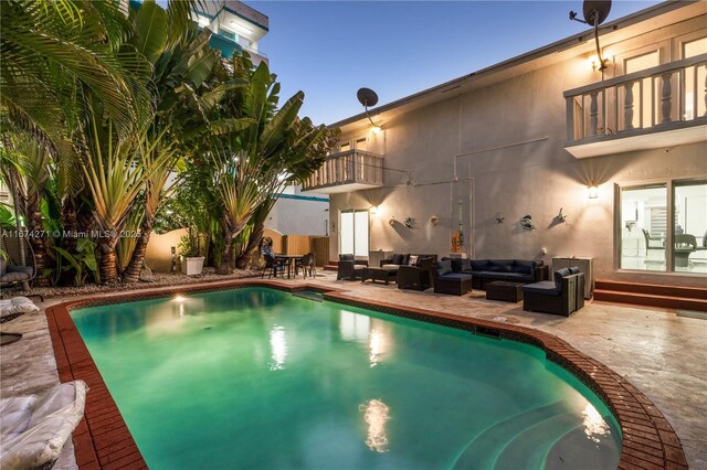 pool at dusk with an outdoor living space and a patio area