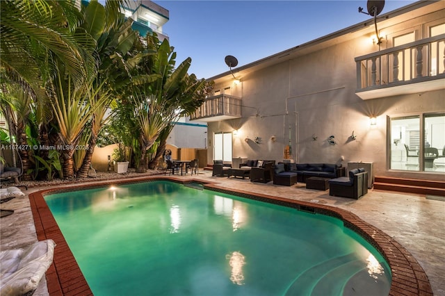 pool at dusk featuring a patio area and outdoor lounge area