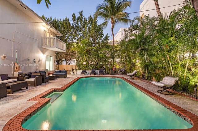 pool at dusk with a patio and outdoor lounge area