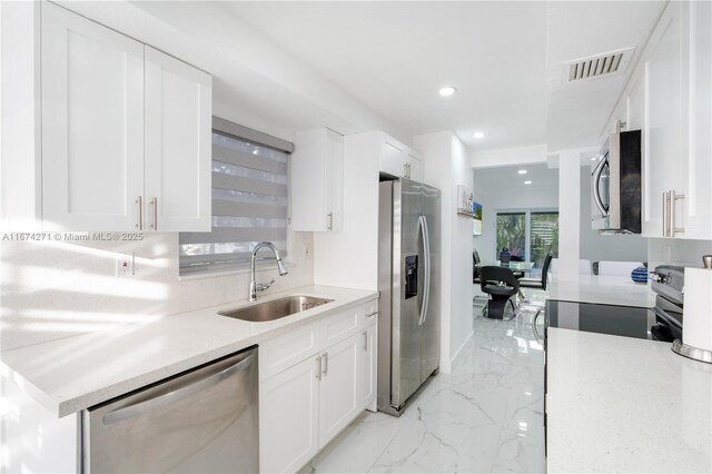 kitchen with stainless steel appliances, white cabinetry, and sink