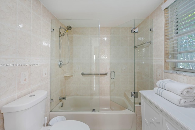 bathroom with bath / shower combo with glass door, tile walls, and toilet