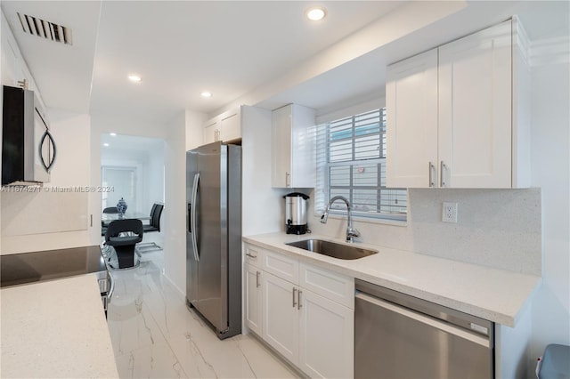 kitchen with white cabinets, stainless steel appliances, sink, and backsplash