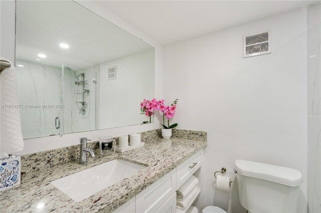 bathroom featuring toilet, vanity, and an enclosed shower