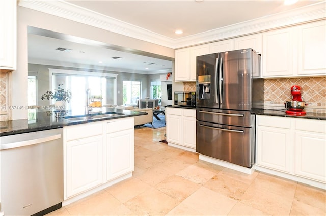 kitchen with tasteful backsplash, crown molding, stainless steel appliances, sink, and dark stone countertops