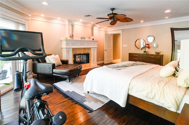 bedroom featuring a fireplace, wood-type flooring, ceiling fan, and crown molding