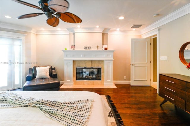 interior space with dark wood-type flooring, a tile fireplace, ceiling fan, and crown molding