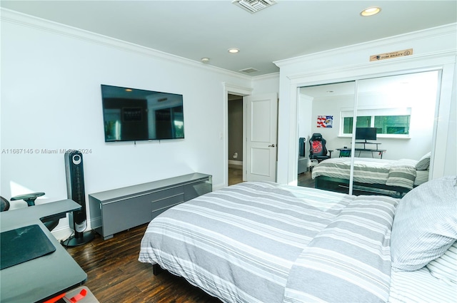 bedroom featuring dark hardwood / wood-style flooring, crown molding, and a closet