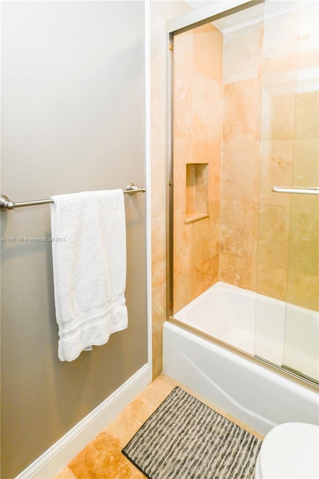 bathroom featuring toilet, tile patterned flooring, and enclosed tub / shower combo