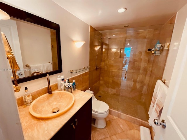 bathroom with tiled shower, vanity, toilet, and tile patterned flooring