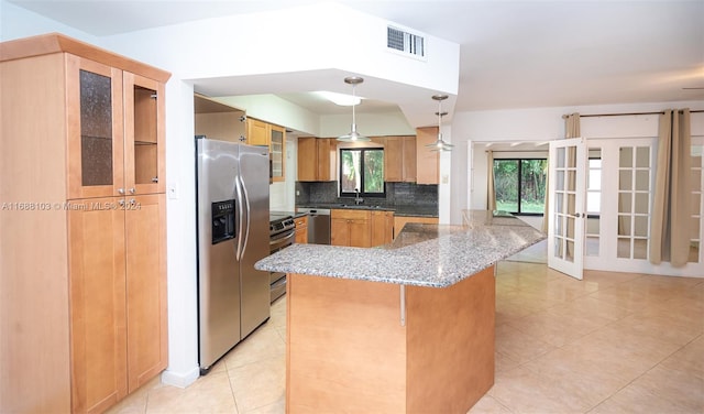 kitchen with sink, stainless steel appliances, dark stone countertops, decorative light fixtures, and decorative backsplash