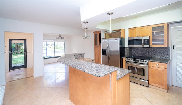 kitchen with pendant lighting, decorative backsplash, light tile patterned floors, appliances with stainless steel finishes, and a breakfast bar area