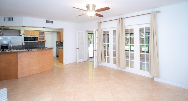 kitchen with appliances with stainless steel finishes, tasteful backsplash, ceiling fan, and a healthy amount of sunlight