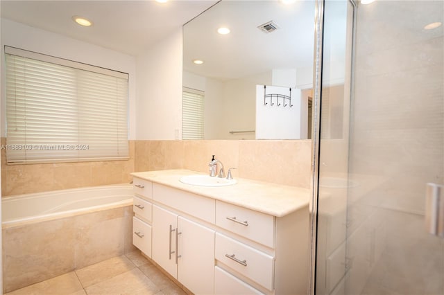 bathroom with tile patterned floors, vanity, and a relaxing tiled tub