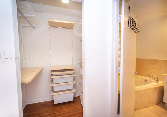 interior space with tiled tub and hardwood / wood-style flooring