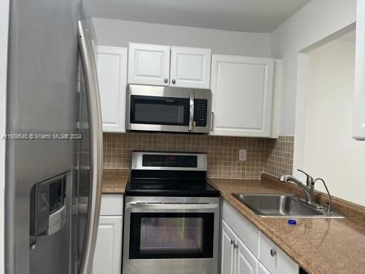 kitchen featuring stainless steel appliances, white cabinetry, sink, and backsplash