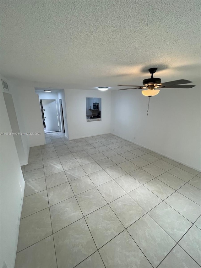 tiled empty room featuring ceiling fan and a textured ceiling