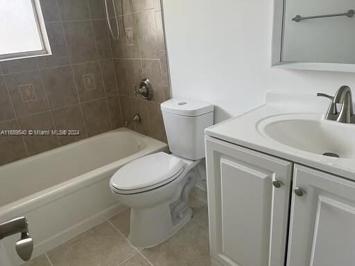 full bathroom featuring tile patterned flooring, vanity, tiled shower / bath combo, and toilet