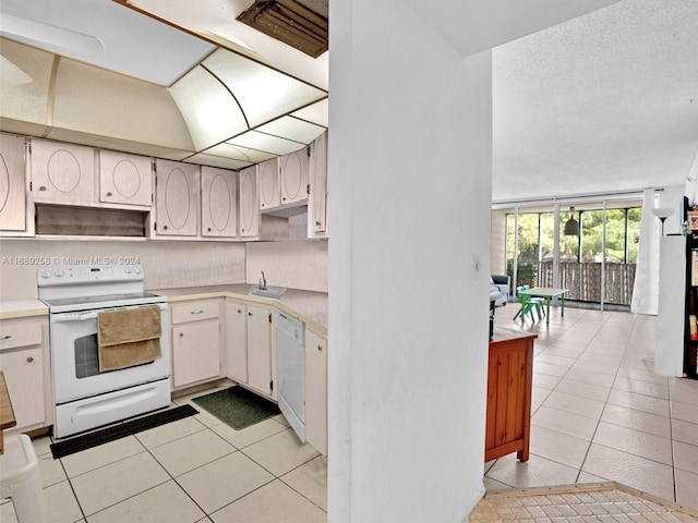 kitchen featuring white appliances, white cabinetry, backsplash, and light tile patterned flooring