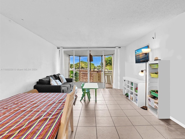 bedroom featuring access to outside, a textured ceiling, light tile patterned floors, and a wall of windows