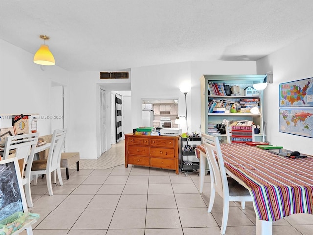 tiled dining space with a textured ceiling