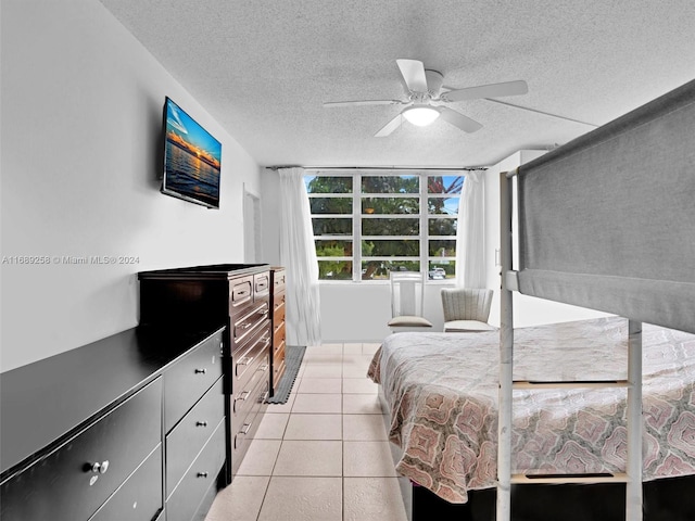 bedroom with a textured ceiling, light tile patterned floors, and ceiling fan