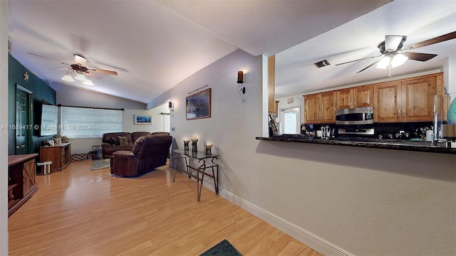 living room featuring light hardwood / wood-style floors, lofted ceiling, and ceiling fan