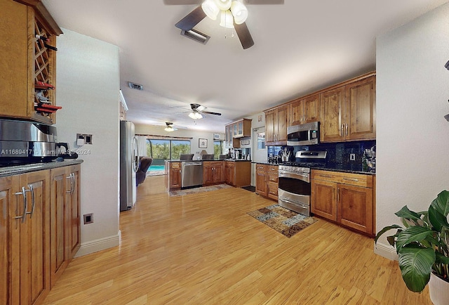 kitchen with tasteful backsplash, kitchen peninsula, appliances with stainless steel finishes, and light hardwood / wood-style floors