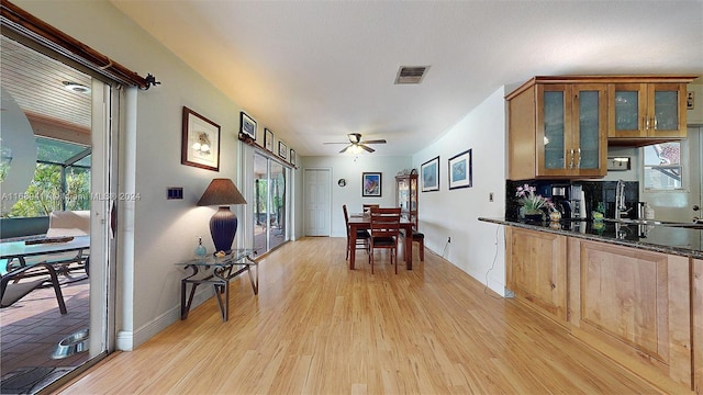 kitchen featuring dark stone counters, ceiling fan, light hardwood / wood-style floors, and plenty of natural light