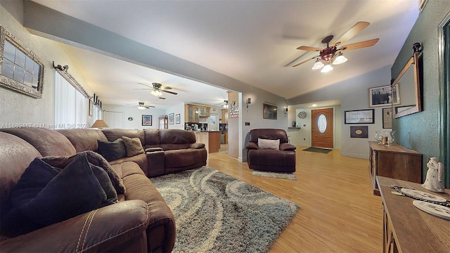 living room featuring a barn door, light wood-type flooring, and lofted ceiling