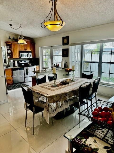 dining room with light tile patterned floors, a wealth of natural light, french doors, and a textured ceiling