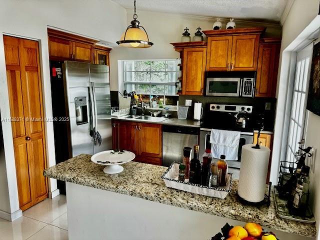 kitchen with decorative light fixtures, plenty of natural light, light stone countertops, and appliances with stainless steel finishes