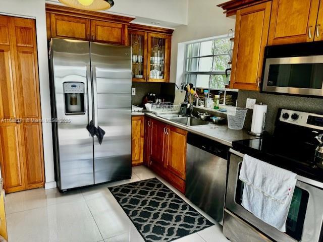 kitchen with tasteful backsplash, appliances with stainless steel finishes, sink, and light tile patterned floors