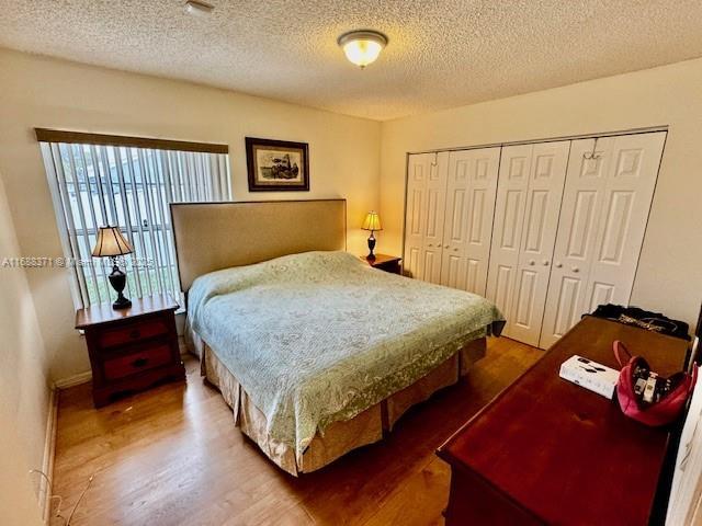 bedroom with wood-type flooring, a closet, and a textured ceiling