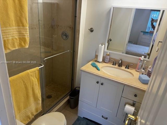 bathroom with vanity, a shower with shower door, tile patterned floors, and toilet