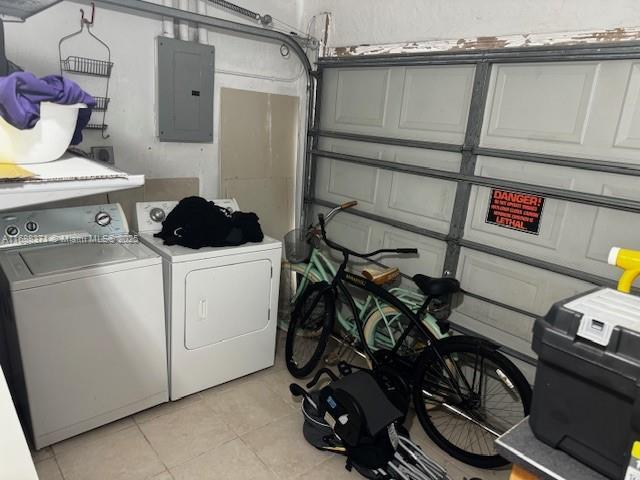 clothes washing area featuring electric panel, washer and clothes dryer, and light tile patterned floors