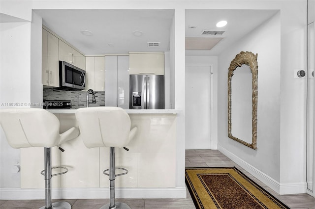 kitchen featuring appliances with stainless steel finishes, a kitchen breakfast bar, and tasteful backsplash