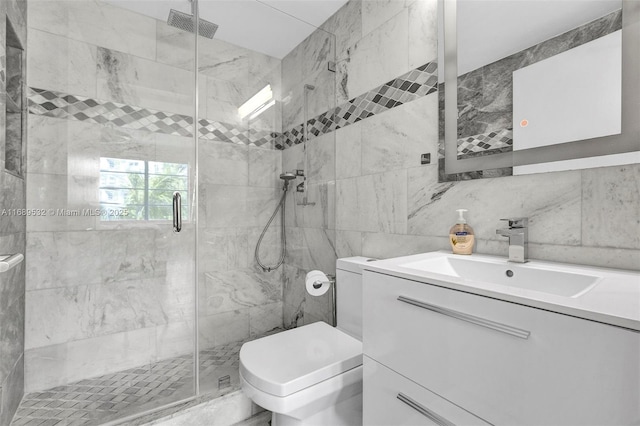 bathroom featuring tile walls, a shower with door, vanity, and toilet