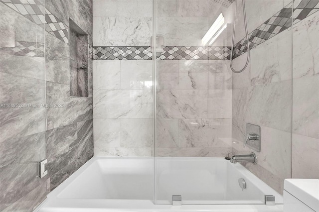 bathroom featuring toilet and tiled shower / bath combo