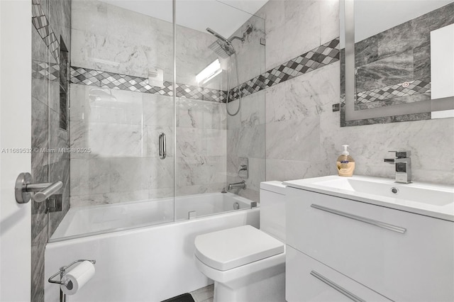 full bathroom with toilet, vanity, tile walls, bath / shower combo with glass door, and backsplash