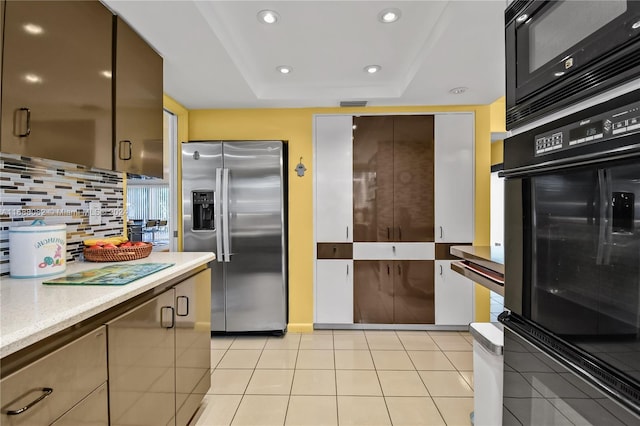 kitchen featuring light tile patterned flooring, stainless steel fridge, a raised ceiling, and decorative backsplash