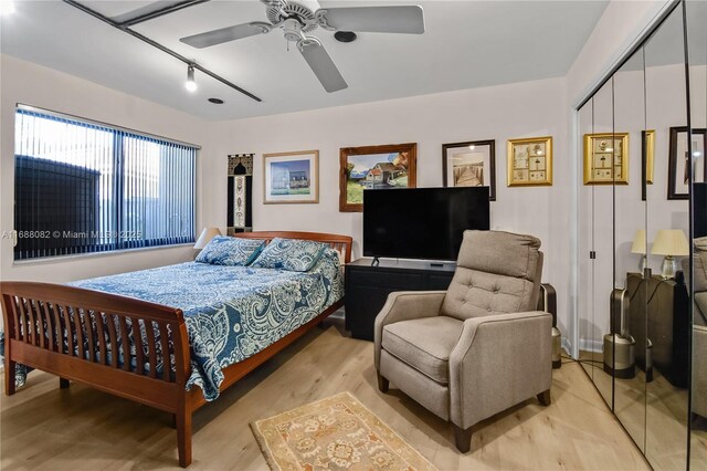 bedroom with ceiling fan, rail lighting, a closet, and light hardwood / wood-style flooring